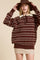 woman wearing a brown striped oversized sweater with a white collar and a beige mini skirt, paired with a brown hat
