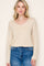 woman wearing a beige long sleeve v-neck sweater paired with high-waisted blue jeans