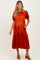 woman wearing an orange maternity dress with puff sleeves and a tiered design, showcasing her baby bump.