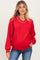 woman wearing a red maternity sweatshirt with a v-neck and white trim, paired with blue jeans and a baby bump visible