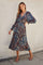 woman wearing a long sleeve paisley print maxi dress with a deep v-neck and tiered skirt, standing on a sidewalk
