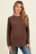 woman wearing a brown long sleeve maternity top with a relaxed fit and a baby bump visible
