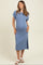 woman wearing a light blue ribbed midi maternity dress with short sleeves and a side split, holding her baby bump