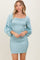 woman wearing a light blue smocked mini dress with puff sleeves and ruffle details