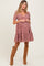 woman wearing a red floral maternity dress with short puff sleeves and a tiered skirt, styled with knee-high boots