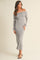 woman wearing a gray off-shoulder long sleeve maxi dress with a fitted silhouette and side slit