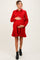 woman wearing a red corduroy maternity dress with a flared skirt and holding her baby bump