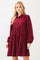 woman wearing a burgundy tiered long sleeve shirt dress with a button-up front and puffed sleeves