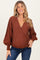 woman wearing a brown polka dot wrap maternity top with balloon sleeves and a v-neckline
