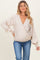 woman wearing a beige maternity wrap top with black polka dots and puffy sleeves, paired with blue jeans