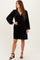 woman wearing a black velvet long sleeve dress with a v-neck and flowy skirt, standing in strappy black heels