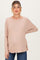 woman wearing a blush pink long sleeve maternity top with a relaxed fit and visible baby bump