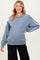 woman wearing a blue maternity sweatshirt with white trim details, showing her baby bump and smiling
