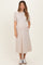 woman wearing a beige maternity midi dress with puff sleeves and pockets