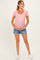 woman wearing a light pink striped maternity top and holding her baby bump, paired with denim shorts
