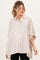 woman wearing a cream striped maternity shirt with a loose fit and button-down front, highlighting a visible baby bump