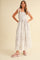 woman wearing a white tie-dye maxi dress with smocked bodice and tie straps, paired with pink platform sandals