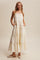 woman wearing a cream tiered maxi dress with colorful embroidery and pockets, styled with braided hair and flat mules