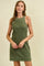 woman wearing an olive green sleeveless dress with white piping details