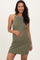 woman wearing a dark green maternity dress with a halter neckline and white piping, holding her baby bump