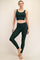 woman wearing a dark green sports bra and matching high-waisted leggings with side pockets