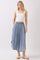woman wearing a white ribbed crop top and a light blue button-down denim maxi skirt with pockets