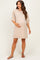 woman wearing a beige short sleeve maternity dress while holding her baby bump