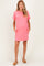 woman wearing a pink maternity dress with a pocket and rolled sleeves, styled casually with sandals and a baby bump visible