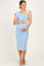 woman wearing a light blue one-shoulder maternity dress, gently holding her baby bump