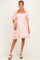 woman wearing a pink floral maternity dress with puff sleeves and a square neckline, holding a small bag