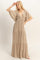 woman wearing a beige maxi dress with a deep v-neck and flowing sleeves, posing gracefully