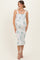 woman wearing a light green floral print maternity dress with square neckline and ruffled hem, showing her baby bump