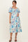 woman wearing a floral print maternity dress with puffed sleeves and a smocked bodice, holding her baby bump