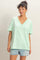 woman wearing a mint green oversized v-neck t-shirt with short sleeves and denim shorts