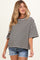 woman wearing a black and white striped maternity top with short sleeves and a relaxed fit, paired with denim shorts