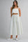 woman wearing a cropped button-up top and a long striped maxi skirt with an elastic waistband and white sneakers
