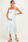 woman wearing a light green maternity dress with smocked bodice and ruffled hem, holding her baby bump