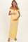 woman wearing a yellow off-the-shoulder maternity dress with buttons, holding her baby bump