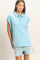 woman wearing a light blue oversized polo shirt with a collar and rolled sleeves, paired with denim shorts