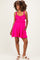 woman wearing a bright pink maternity dress with ruffle details and adjustable straps