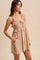 woman wearing a beige ruffled sundress with embroidery details and pockets, standing in profile against a neutral background