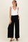 woman wearing a white sleeveless maternity top and black wide-leg maternity pants with pockets