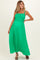 woman wearing a vibrant green maternity maxi dress with a smocked top and flowing skirt, showcasing her baby bump