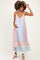 woman wearing a pink and blue floral maternity dress with spaghetti straps and ruffle hem, holding her baby bump