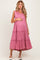 woman wearing a pink sleeveless maternity dress with tiered ruffles and holding her baby bump