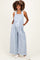 woman wearing a blue floral print maternity overall with wide legs and holding her baby bump