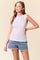 woman wearing a light purple sleeveless top with a floral pattern and paired with denim shorts