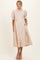 woman wearing a beige maternity dress with paisley print, short puff sleeves, and button front detail, showcasing her baby bump