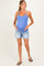 woman wearing a light blue maternity tank top and denim shorts, showing her baby bump