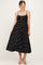 woman wearing a black polka dot maternity dress with smocked bodice and adjustable straps